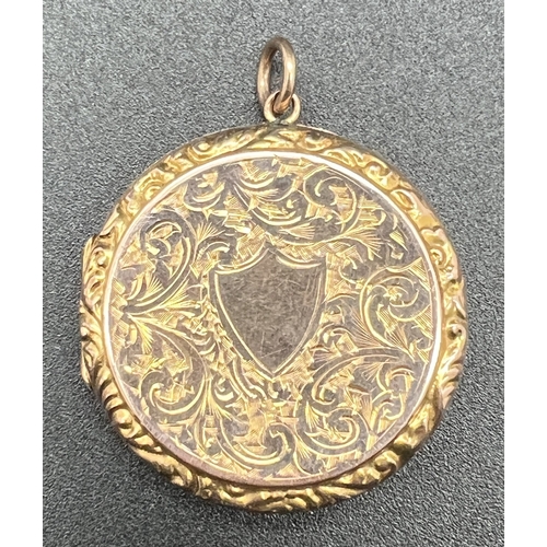 A large antique 9ct rose gold circular shaped locket, heavily engraved with scroll and foliate design to both sides. With central empty shield shaped cartouche. Marked 9ct Back & Front. Approx. 6.4cm diameter.