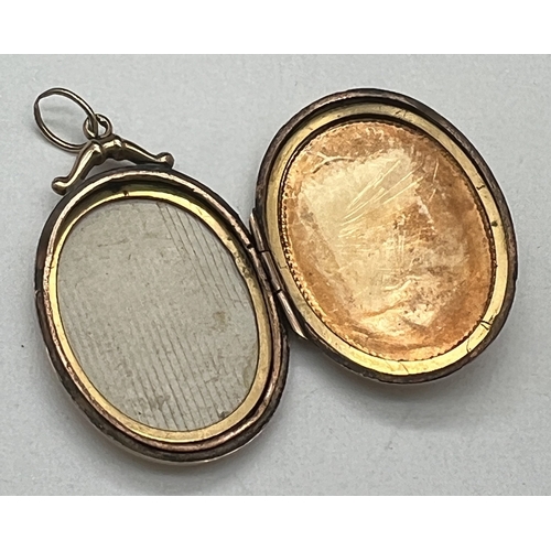 1093 - An antique 15ct gold oval shaped locket set with a trio of rose cut diamonds in a central engraved f... 