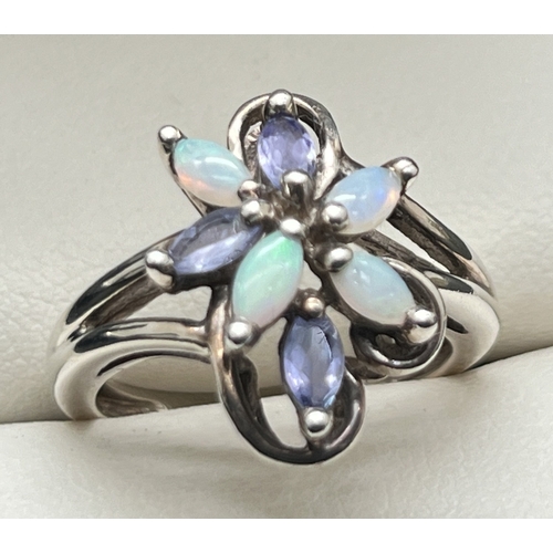 1163 - An unmarked white metal dress ring of floral design, set with marquis cut opals & tanzanite stones. ... 