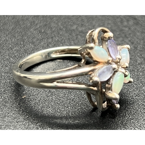 1163 - An unmarked white metal dress ring of floral design, set with marquis cut opals & tanzanite stones. ... 