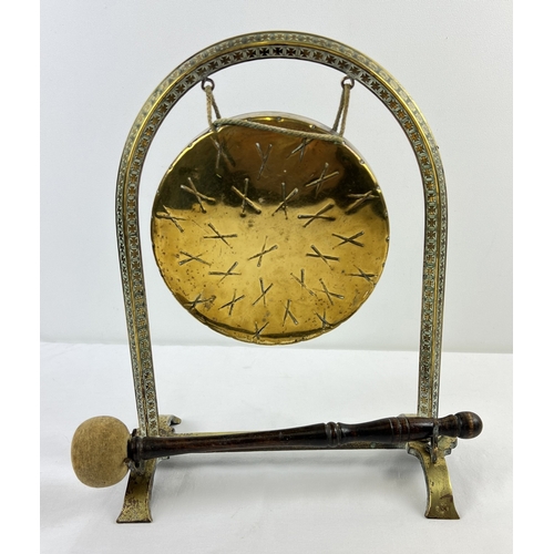 1194 - An antique brass freestanding dinner gong with turned wooden handled beater. Approx. 33.5cm tall.