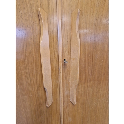 1368 - A mid century teak double wardrobe with moulded handles and complete with key. Interior has hanging ... 