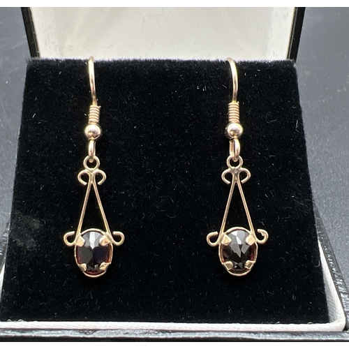 1005 - A pair of 9ct gold, garnet set drop earrings with hallmarked hooked posts. Approx. 3.5cm long. Mount... 