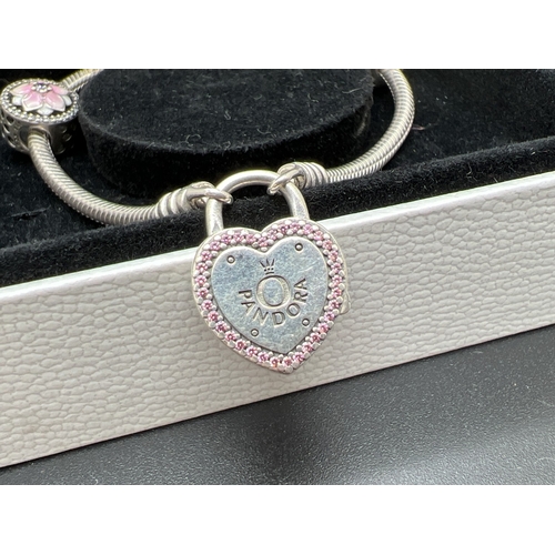 1016 - A boxed Pandora charm bracelet with pink stone set padlock clasp and 5 enamelled and stone set charm... 