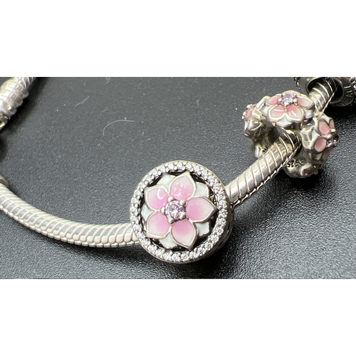 1016 - A boxed Pandora charm bracelet with pink stone set padlock clasp and 5 enamelled and stone set charm... 