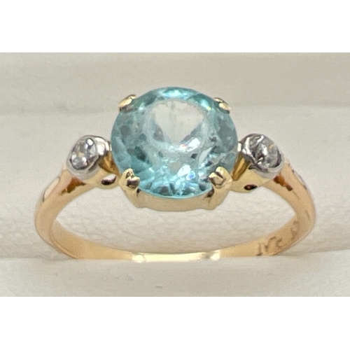 1045 - A vintage 18ct gold blue topaz and diamond dress ring. Central round cut blue topaz with a small bez... 