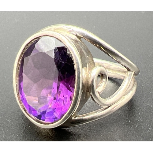 1056 - A modern design silver and amethyst dress ring. Central bezel set large oval cut amethyst, open shou... 