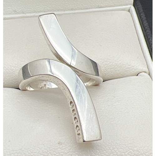 1060 - A 925 silver modern twist design dress ring by Gucci. Silver marks throughout and Gucci name to ride... 