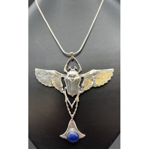 1061 - A large silver pendant modelled as a flying beetle with suspended lapis cabochon, on an 18