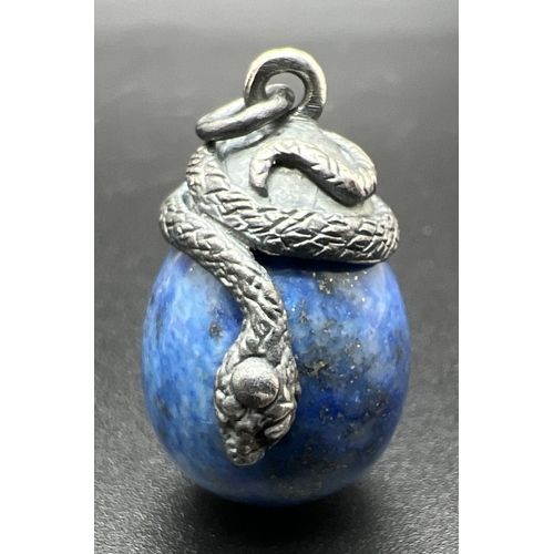 1065 - A pendant modelled as a white metal snake coiled over an egg shaped piece of lapis lazuli. Total len... 