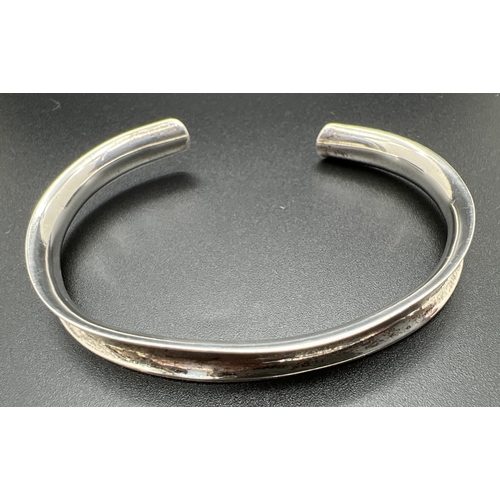 1021 - A silver cuff bangle together with a silver round brad and faceted iridescent bead bracelet with T B... 