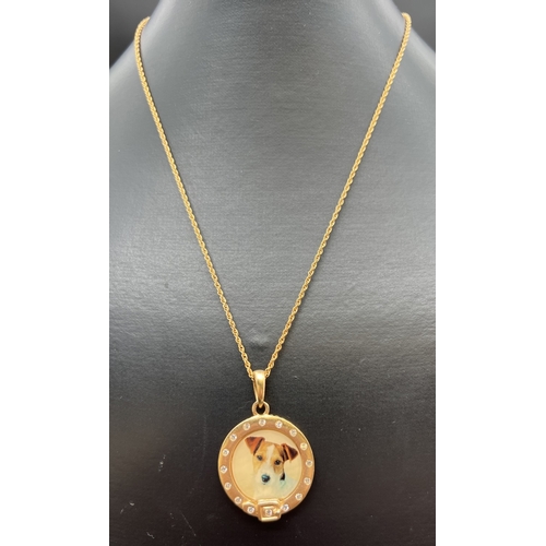 1067 - A vintage gold plated circular shaped pendant with enamelled panel featuring a Jack Russell dog. Cle... 