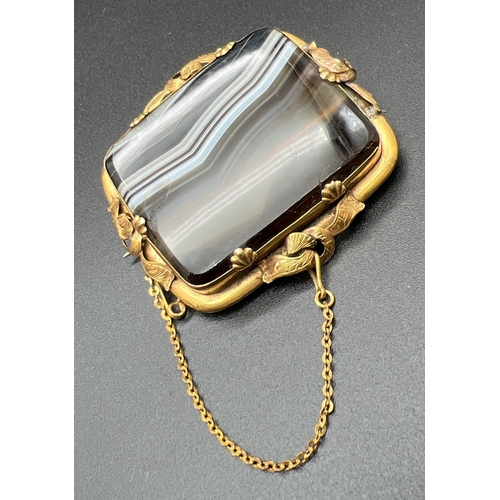 1069 - A large Victorian square shaped banded agate brooch set in an ornate unmarked yellow metal mount. Wi... 