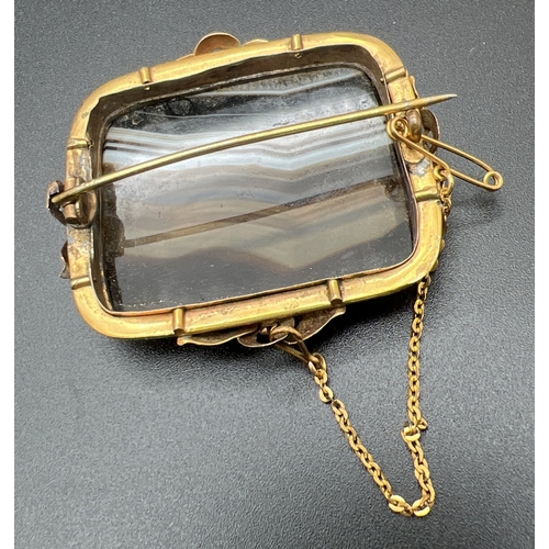 1069 - A large Victorian square shaped banded agate brooch set in an ornate unmarked yellow metal mount. Wi... 