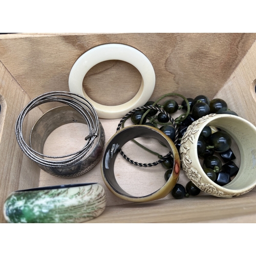 1073 - A small wooden crate of assorted vintage costume jewellery to include chunky fashion bangles and sta... 