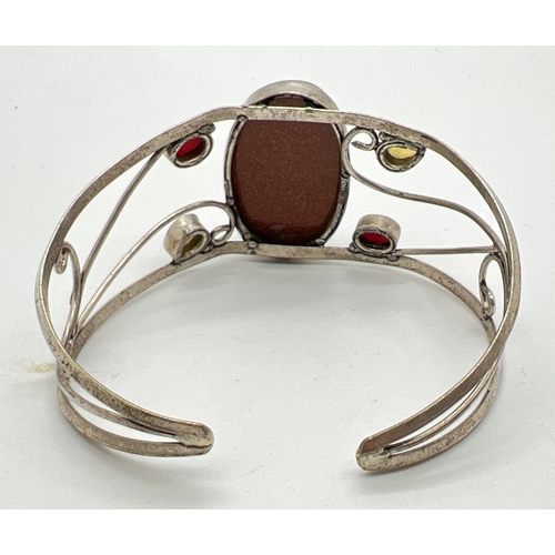 1098 - A silver modern design open scroll work cuff bangle set with large central brown sandstone, 2 oval c... 