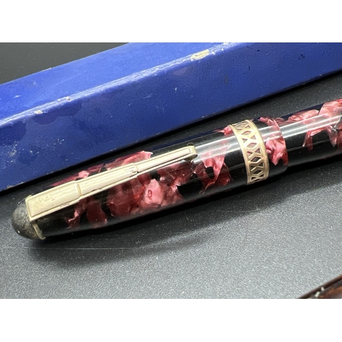 1132 - 2 vintage fountain pens. A pink marble effect pen by Osmiroid with decorative gold plated band to li... 