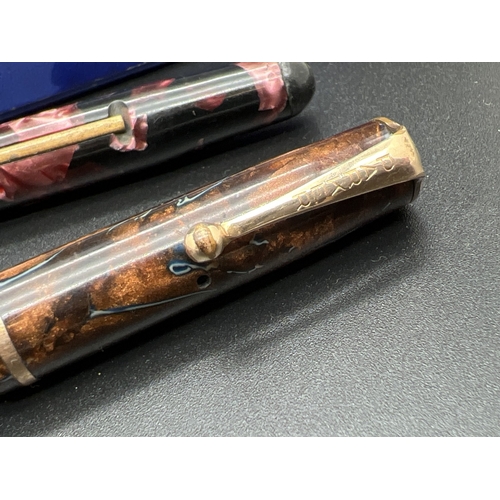 1132 - 2 vintage fountain pens. A pink marble effect pen by Osmiroid with decorative gold plated band to li... 