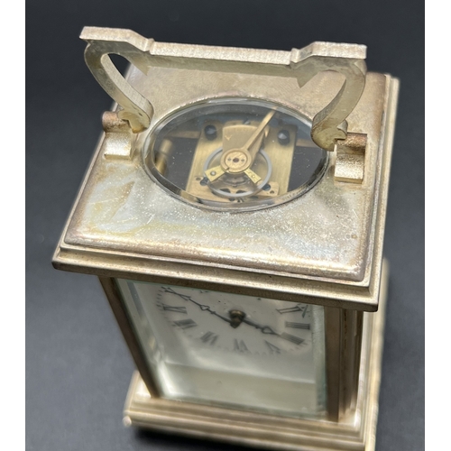 1173 - A small silver plated carriage clock with bevel edged glass panels and enamelled face with Roman Num... 