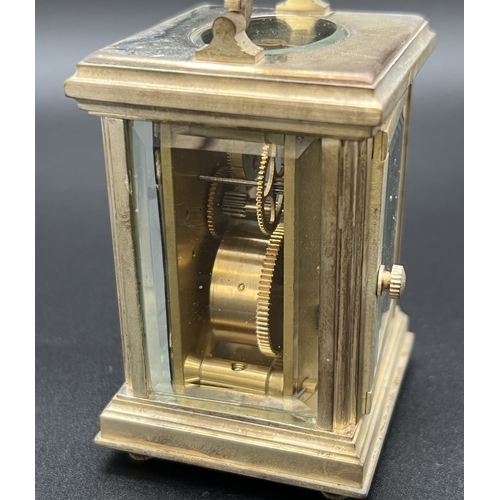 1173 - A small silver plated carriage clock with bevel edged glass panels and enamelled face with Roman Num... 