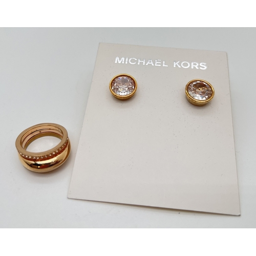 80 - 2 items of Michael Kors jewellery. A gold tone stone set double intertwined band ring set with clear... 