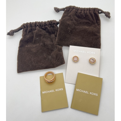 80 - 2 items of Michael Kors jewellery. A gold tone stone set double intertwined band ring set with clear... 