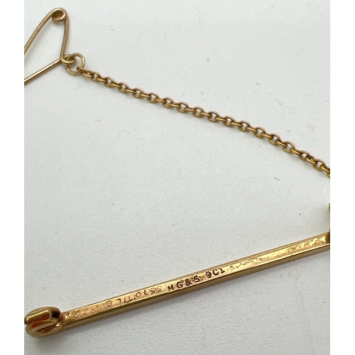 87 - A 9ct gold tie pin with safety chain and engine turned decoration. Gold marks to back. Total weight ... 