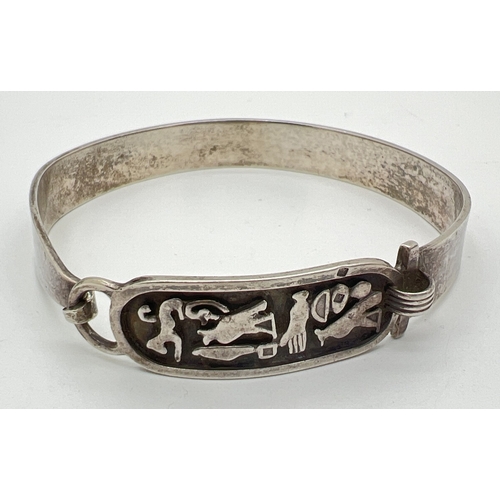 127 - An Eygitian silver bangle with Hieroglyph decorated panel and hook and eye clasp. Worn silver marks ... 