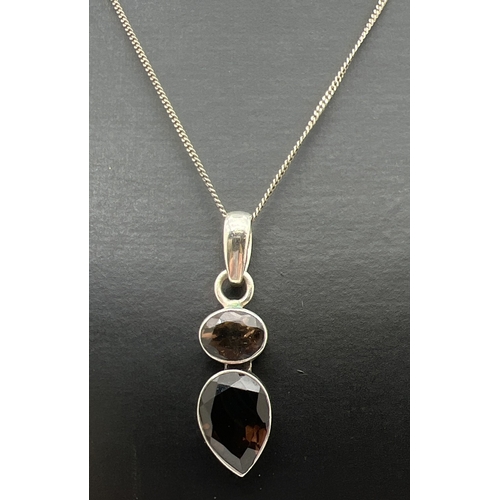 169 - A modern design silver pendant set with oval cut and a pear cut smoked quartz stones. On an 18