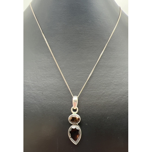 169 - A modern design silver pendant set with oval cut and a pear cut smoked quartz stones. On an 18