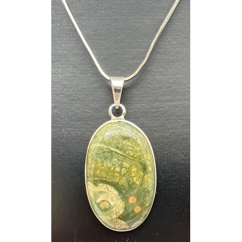 173 - A modern oval shaped silver pendant set with a cabochon of green jasper. On an 18