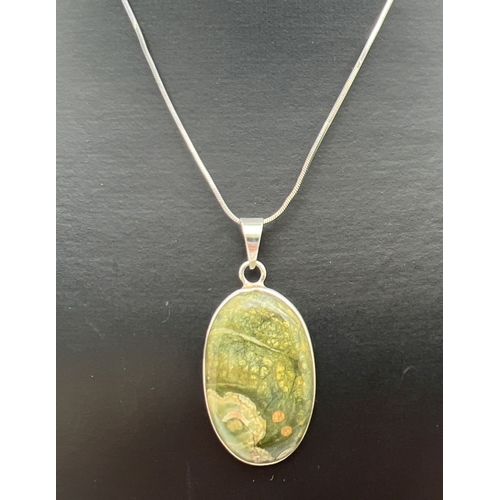 173 - A modern oval shaped silver pendant set with a cabochon of green jasper. On an 18