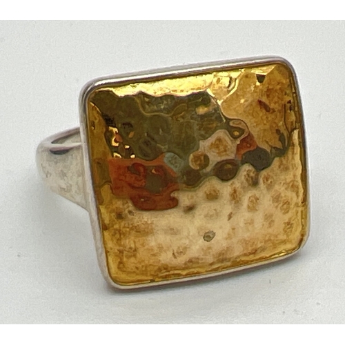 176 - A modern design silver dress ring by The Genuine Gem Company. Square shaped top with silver gilt ham... 