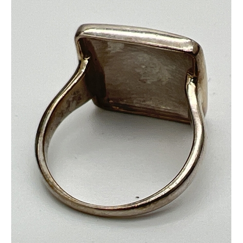 176 - A modern design silver dress ring by The Genuine Gem Company. Square shaped top with silver gilt ham... 