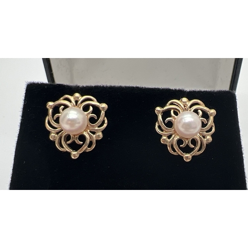 196 - A pair of 9ct gold pearl set stud earrings with decorative pierced work mounts. Gold marks on posts.... 