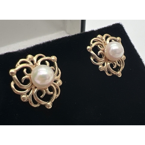 196 - A pair of 9ct gold pearl set stud earrings with decorative pierced work mounts. Gold marks on posts.... 