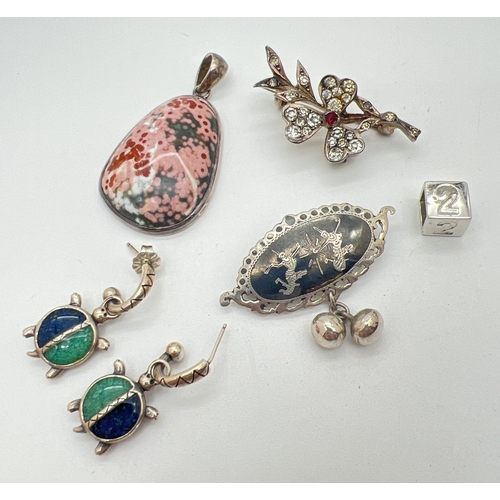 200 - A small collection of silver jewellery. To include a natural stone pendant in pink tones, a Siam sil... 