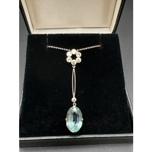 An Art Deco 15ct gold and platinum, aquamarine and diamond pendant necklace. A fine belcher chain fixed to an open circle of 6 round cut diamonds. With attached marquise style bale, bezel set diamond and oval cut aquamarine drop. Side of bale marked '15ct & Plat', aquamarine approx. 3ct, total diamonds approx. 0.34ct. Total length approx. 19.5 inches.