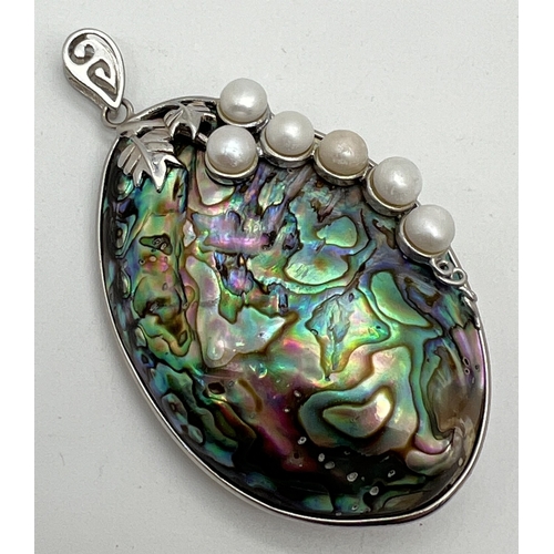 1002 - A large oval abalone shell pendant in a silver mount with silver leaf overlay and freshwater pearl d... 