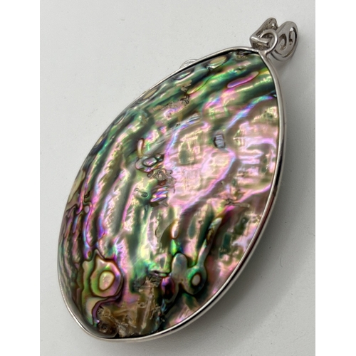 1002 - A large oval abalone shell pendant in a silver mount with silver leaf overlay and freshwater pearl d... 