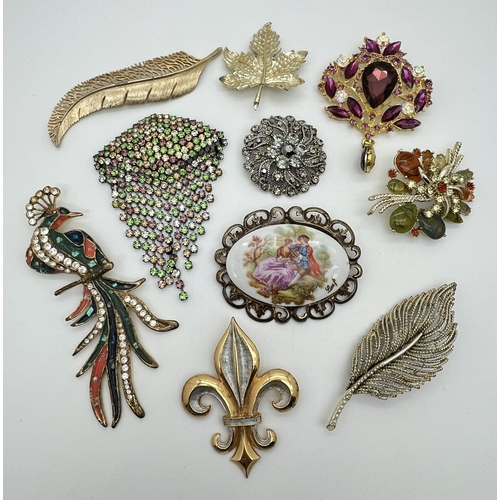 1047 - 10 larger statement brooches in various styles, some stone set. To include 2 feather design brooches... 