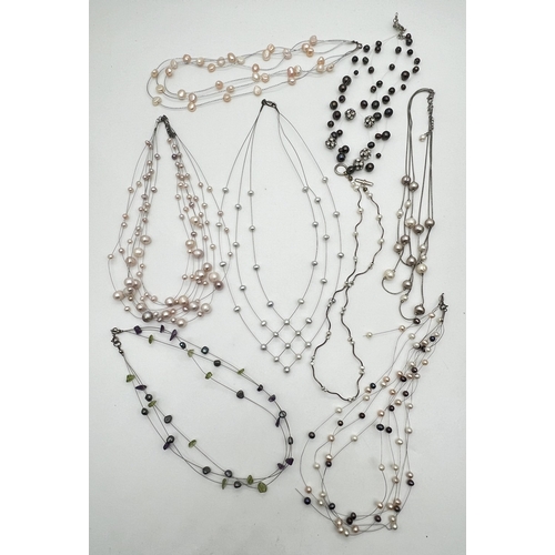1049 - A faux suede box containing 8 assorted floating pearl style necklaces of varying styles and colours.... 
