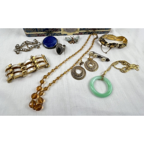 1050 - A tin of assorted vintage costume jewellery to include a silver Ruskin Pottery blue coloured brooch,... 