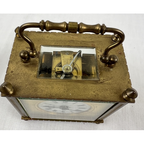 1239 - A small antique brass carriage clock with white enamel face. Black roman numeral hour markers and ha... 