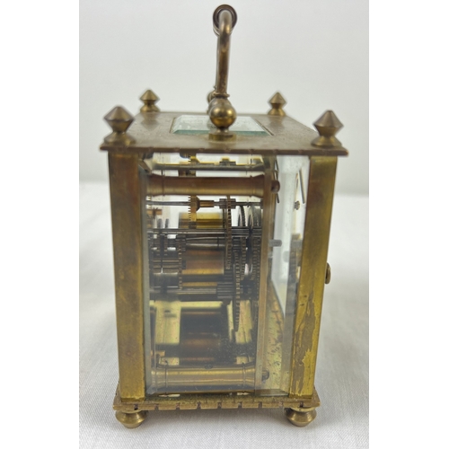 1239 - A small antique brass carriage clock with white enamel face. Black roman numeral hour markers and ha... 