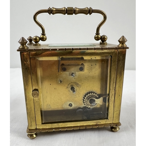 1239 - A small antique brass carriage clock with white enamel face. Black roman numeral hour markers and ha... 