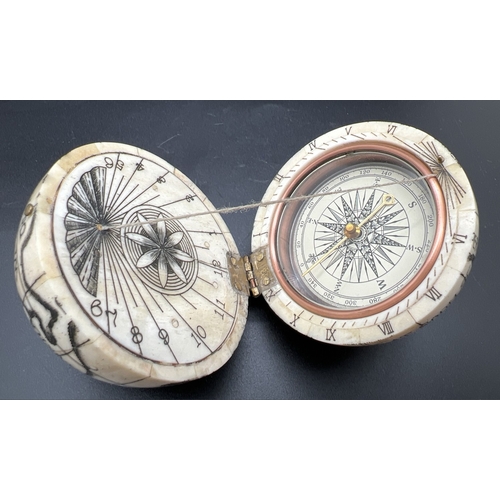 1305 - A Scrimshaw style carved globe with inset compass to interior. Possibly bone, approx. 7cm diameter.