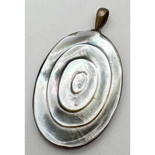 1014 - A large oval shaped carved pearl shell pendant in silver mount. Silver marks on bale. Approx. 6.5cm ... 