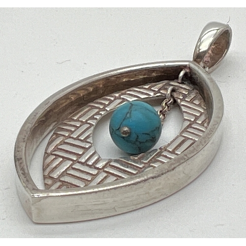 1019 - A silver and turquoise marquise shaped open design pendant. With suspended parquet decorated insert ... 