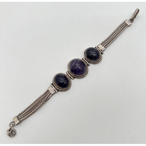 1036 - A 925 silver bracelet set with 3 large amethyst oval cabochons set in hinged rope design mounts. Wit... 